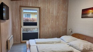 Un dormitorio con dos camas, una ventana con persianas, un radiador y un cuadro en la pared.