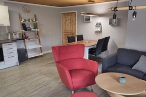 Ein stilvolles Wohnzimmer mit einem roten Sessel, einem grauen Sofa, einem Holzesstisch und einem Couchtisch.