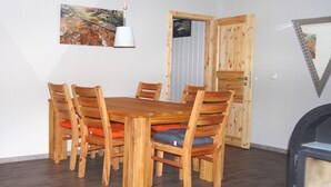 Un comedor con una mesa y sillas de madera, un cuadro en la pared y una puerta con ventanal.