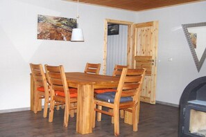 Ein Essbereich mit einem Holztisch und Stühlen, einem Bild an der Wand und einer Tür mit Fenster.