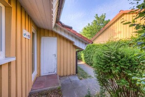 A yellow building with a white door and a sign indicating room number 102. - Double bungalow in country house style with terrace in the Mirow holiday park (Granzow)