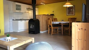 A cozy living space with a kitchen, dining area, and a fireplace. - Double bungalow in country house style with terrace in the Mirow holiday park (Granzow)