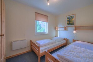 A room with two wooden beds, a radiator, a window with a blind, and a painting on the wall. - Double bungalow in country house style with terrace in the Mirow holiday park (Granzow)