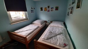 A room with two single beds, a window with a blind, and several framed pictures on the wall. - Double bungalow in country house style with terrace in the Mirow holiday park (Granzow)