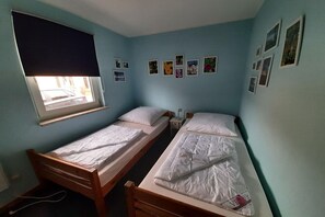 A room with two single beds, a window with a blind, and several framed pictures on the wall. - Double bungalow in country house style with terrace in the Mirow holiday park (Granzow)