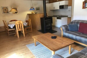 Ein gemütliches Wohnzimmer mit einer Couch, einem Holztisch und einer Küchenzeile mit Herd.