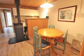 Un intérieur en bois avec une table ronde et des chaises, un radiateur noir et un tableau accroché au mur.