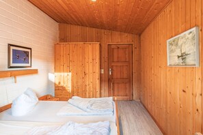 Una habitación con paneles de madera, una cama, un armario y una puerta.