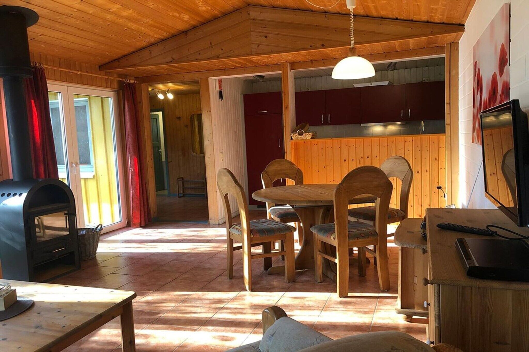 A wooden interior with a dining area, a kitchen, and a fireplace.