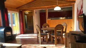 Un intérieur en bois comprenant un coin repas, une cuisine et une cheminée.