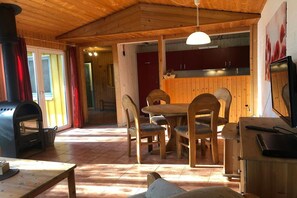 A wooden interior with a dining area, a kitchen, and a fireplace. - Komfortabler Doppelbungalow mit Terrasse im Ferienpark Mirow (Granzow)