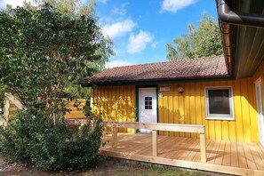 A yellow building with a tiled roof, a white door, and a small window. - Komfortabler Doppelbungalow mit Terrasse im Ferienpark Mirow (Granzow)