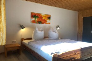 A bedroom with a wooden bed, two bedside lamps, a nightstand, and a wall-mounted painting. - Komfortabler Doppelbungalow mit Terrasse im Ferienpark Mirow (Granzow)