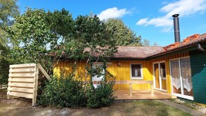 Un bâtiment jaune avec une cheminée, une structure en bois et une petite fenêtre.