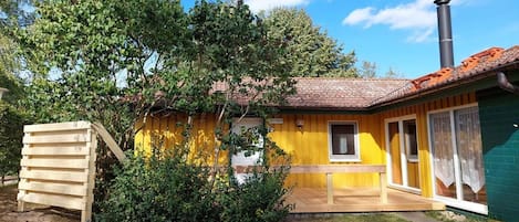 A yellow building with a chimney, a wooden structure, and a small window.