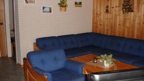 A room with a blue sectional sofa, a wooden coffee table, and a television. - Praktischer Doppelbungalow mit Terrasse im Ferienpark Mirow (Granzow)