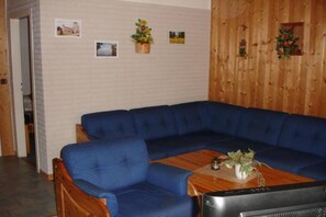 A room with a blue sectional sofa, a wooden coffee table, and a television. - Praktischer Doppelbungalow mit Terrasse im Ferienpark Mirow (Granzow)