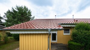 A yellow building with a red-tiled roof, a small window, and a door. - Praktischer Doppelbungalow mit Terrasse im Ferienpark Mirow (Granzow)