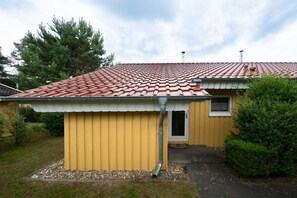 A yellow building with a red-tiled roof, a small window, and a door. - Praktischer Doppelbungalow mit Terrasse im Ferienpark Mirow (Granzow)