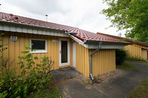 Ein eingeschossiges Gebäude mit roten Ziegeln auf dem Dach, einer Haustür und einem kleinen Fenster.
