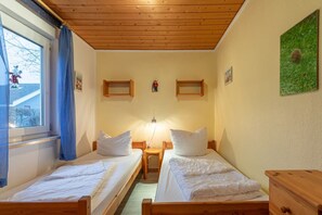 A room with two wooden beds, a nightstand, a lamp, and a window with curtains. - Stilvoll eingerichteter Doppelbungalow mit Terrasse im Ferienpark Mirow (Granzow)