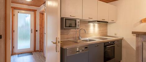 A modern kitchen with stainless steel appliances, wooden flooring, and a wooden ceiling.