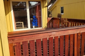 A yellow building with a wooden deck and a glass door with a blue decorative item. - Gemütlicher Doppelbungalow im Ferienpark Mirow mit Terrasse (Granzow)