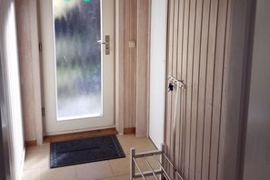 Ein Zimmer mit einer Schiebetür, einer Holztür, einer Fußmatte und einem Metallregal.