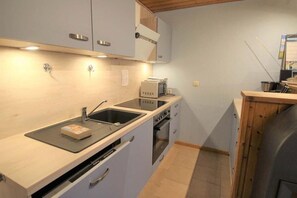 Eine kleine Küche mit Spüle, Mikrowelle, Toaster und Backofen.
