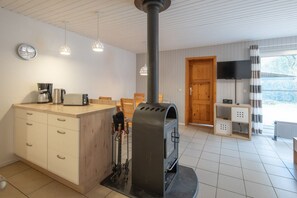 Eine moderne Küche mit Holzofen, Kaffeemaschine und Fernseher.