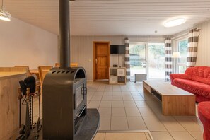 Ein Wohnzimmer mit Kamin, einem roten Sofa, einem Holztisch und einem Fernseher.