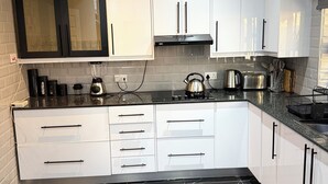 Una cocina moderna con armarios blancos, encimera negra y suelo de mármol negro.