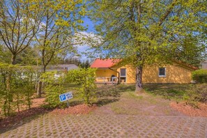 A building with a red roof, a small porch, and a parking sign. - Gemütlicher Doppelbungalow mit Garten und Terrasse im Ferienpark Mirow (Granzow)