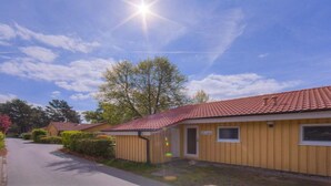 Eine Reihe von eingeschossigen Gebäuden mit rotem Ziegeldach und einem gepflasterten Weg, bewölkter Himmel.