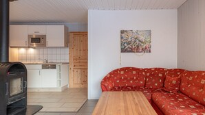 Ein kompakter Wohnbereich mit Küchenzeile, einer Couch und einem Holztisch.