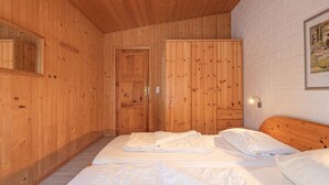 Ein Zimmer mit Holzwänden, einem Bett, einem Kleiderschrank und einem gerahmten Bild an der Wand.
