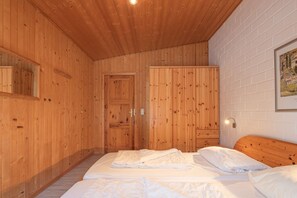 Ein Zimmer mit Holzwänden, einem Bett, einem Kleiderschrank und einem gerahmten Bild an der Wand.