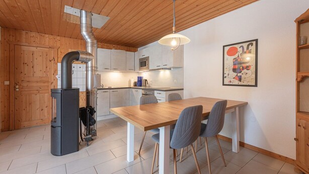 Eine moderne Küche mit Holzschränken, einem eingebauten Herd und einem Essbereich mit Tisch und Stühlen.