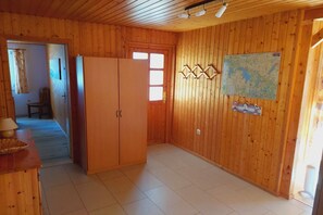 Ein Zimmer mit Holzwänden, einem großen Kleiderschrank, einer Karte an der Wand und einer Tür zu einem weiteren Raum.