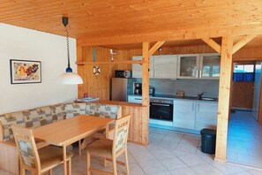 A wooden interior with a dining area, kitchen, and a view of the outside. - Schöner Doppelbungalow mit Terrasse und Garten in Mirow (Granzow)