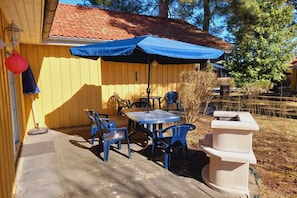 Eine Terrassengaststätte mit Tisch und Stühlen, einem überdachten Bereich und einer Steinstruktur.