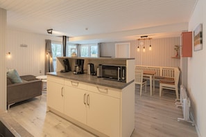 A compact kitchen with a microwave, coffee maker, and a dining area with a bench and table. - Modern eingerichteter Doppelbungalow mit Garten in Mirow (Granzow)