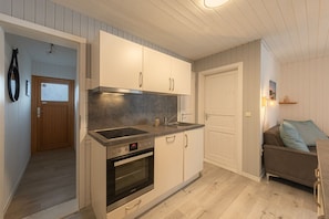 A compact kitchen with white cabinets, a built-in oven, and a countertop. - Modern eingerichteter Doppelbungalow mit Garten in Mirow (Granzow)