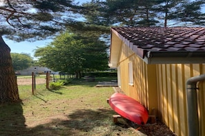 A yellow building with a tiled roof, a red canoe, and a tree in the foreground. - Modern eingerichteter Doppelbungalow mit Garten in Mirow (Granzow)