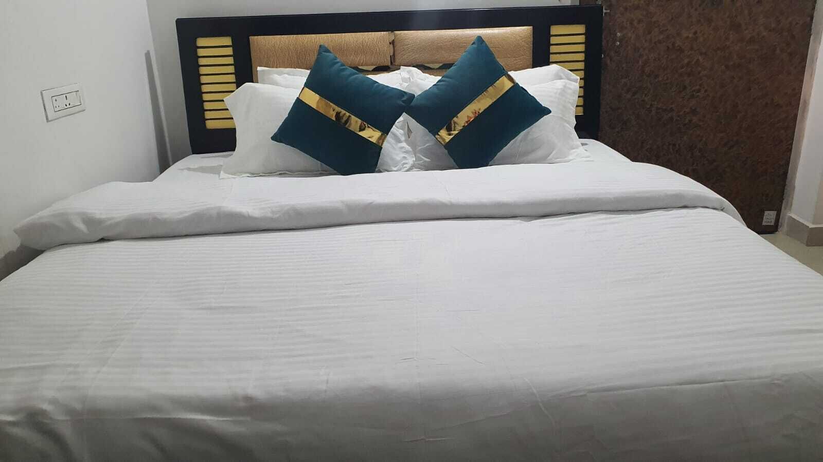 Una cama bien tendida con ropa de cama blanca y dos almohadas decorativas.