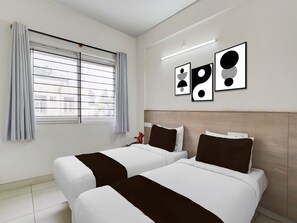 A hotel room with two beds, a window with blinds, and three black-and-white framed pictures on the wall. - Premium KSR Bengaluru City Junction Gurudev (Bengaluru)
