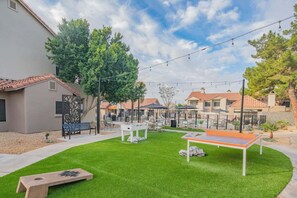 A residential area with a well-maintained lawn, outdoor seating, and a pool area. - Near TPC & Shops | Pool, Gym, Balcony & Parking (Scottsdale)