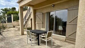An outdoor patio with a table and chairs, a staircase, and a sliding glass door. - Les 4 Sources / Apartment with a view, terrace, air conditioning, and private parking (Villelaure)
