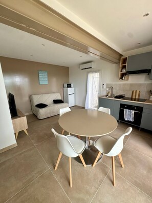 A compact living space with a dining area, kitchenette, and a sofa. - Les 4 Sources / Apartment with a view, terrace, air conditioning, and private parking (Villelaure)