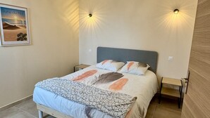 A bedroom with a bed, a nightstand, and a wall-mounted light fixture. - Les 4 Sources / Apartment with a view, terrace, air conditioning, and private parking (Villelaure)
